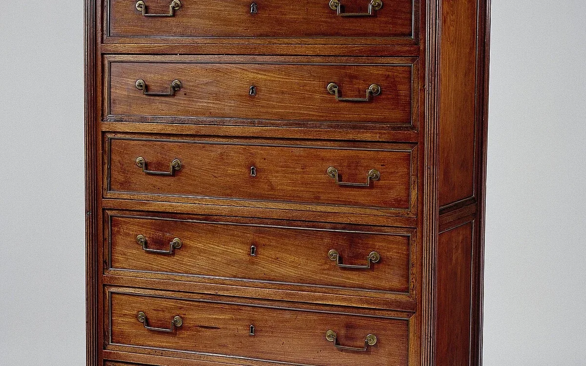 Several wooden drawer fronts with small metal handles fill the front of a chest