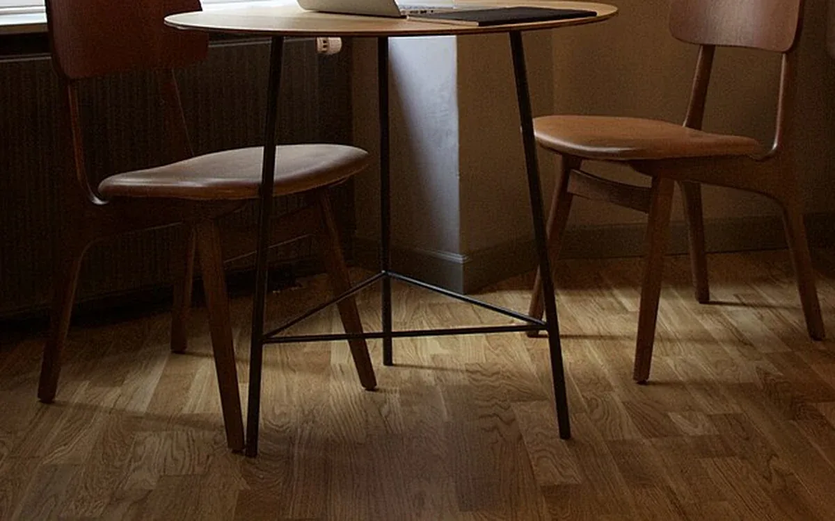 Wooden chairs and the edge of a table stand on a wooden floor