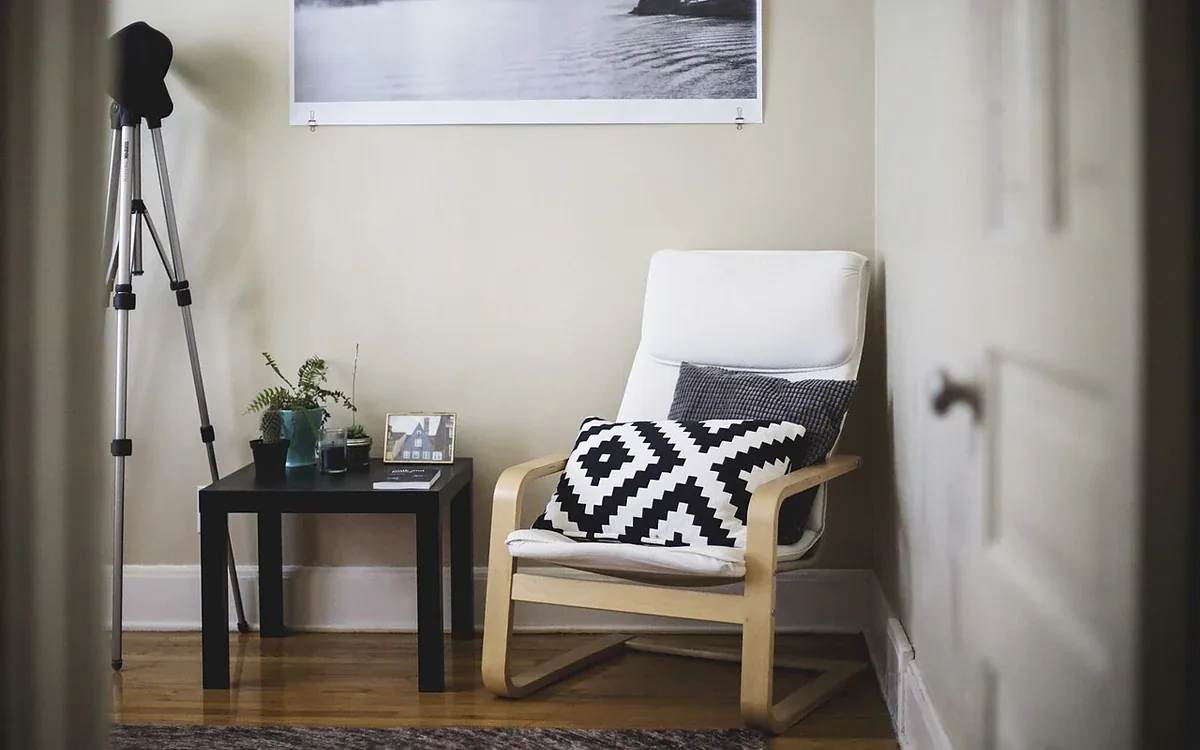 An upholstered armchair with a patterned cushion stands beside a small dark table