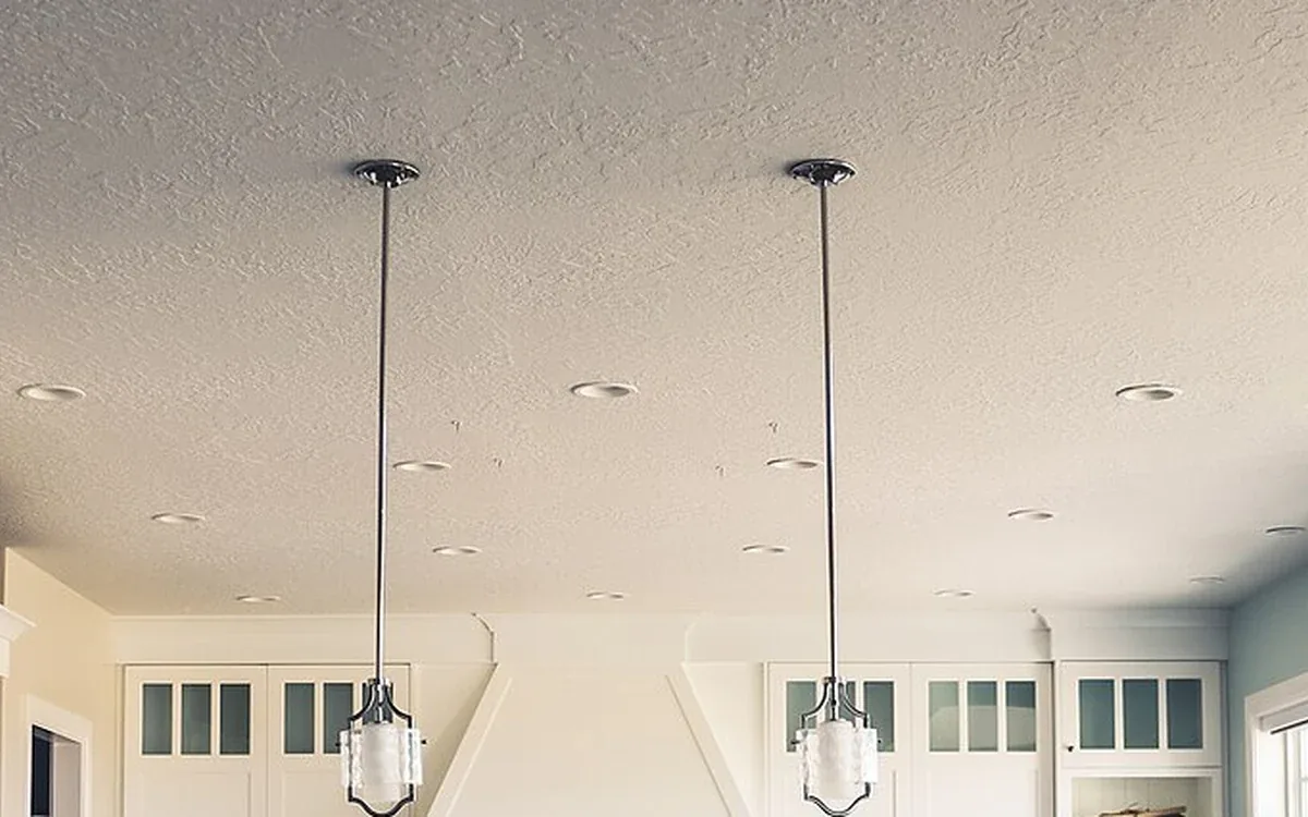 Two hanging lights descend above pale upper kitchen cupboards