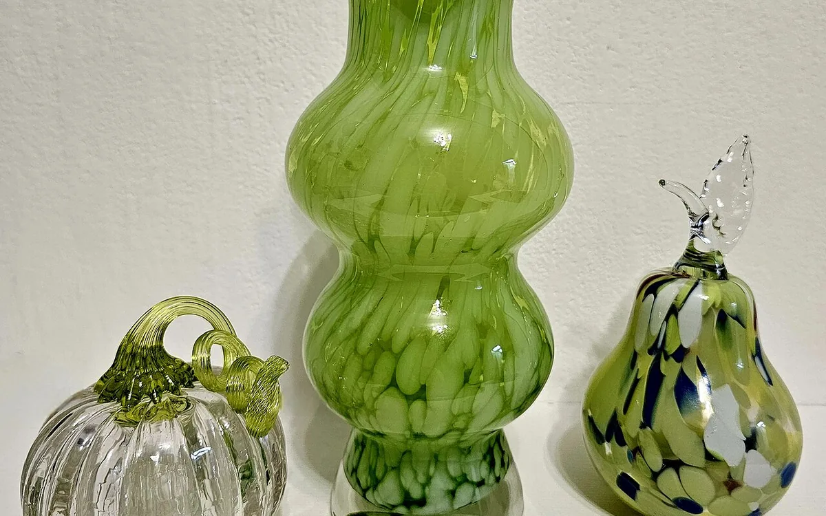 Green glass vase beside a clear glass pumpkin with a green stem and a green pear-shaped glass ornament.
