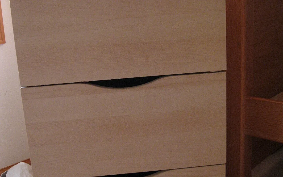 Broad pale wooden drawer fronts have dark recessed handholds