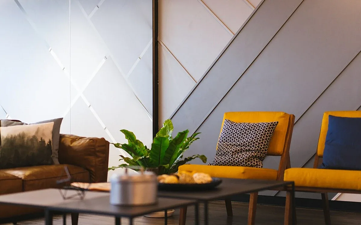 Yellow upholstered chairs and a darker sofa surround a low round table