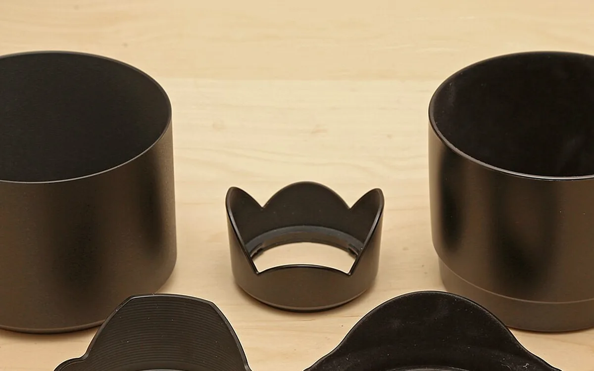 Different shaped black lens hoods on a wooden tabletop
