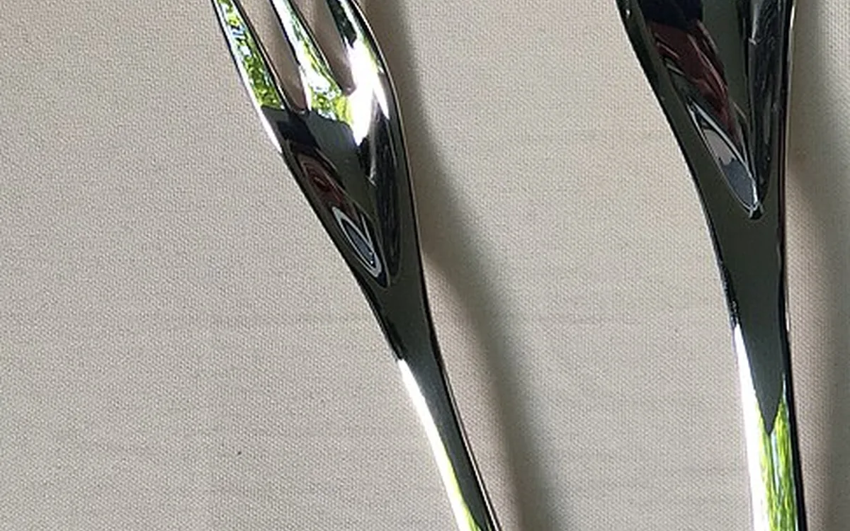 Close-up of two polished metal utensils resting on beige woven fabric.