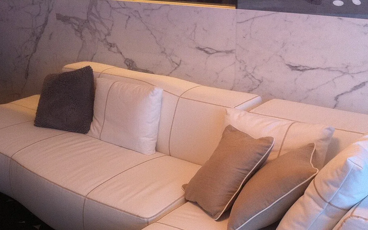 A pale sectional sofa with loose cushions curves around a furnished room