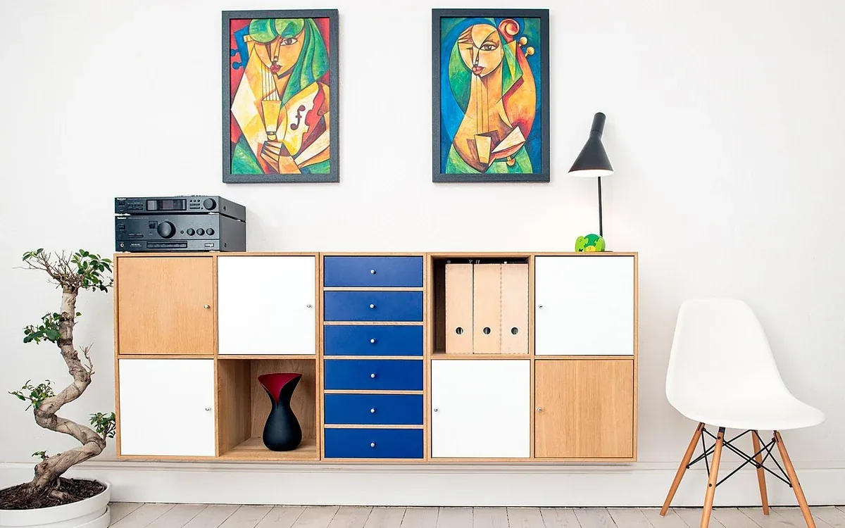 A cabinet combines open storage cubes, pale cupboards and blue drawers beside a white chair