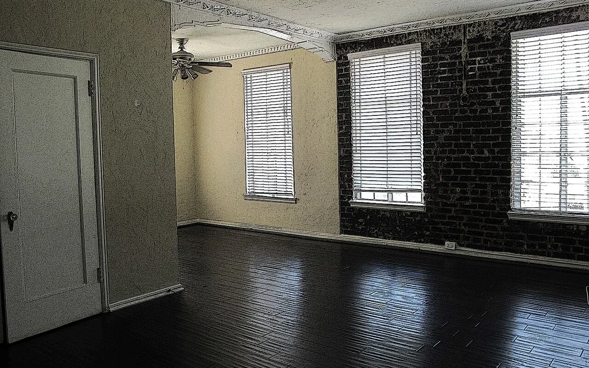An empty pale-walled room has dark wooden flooring, several tall windows and a closed white door