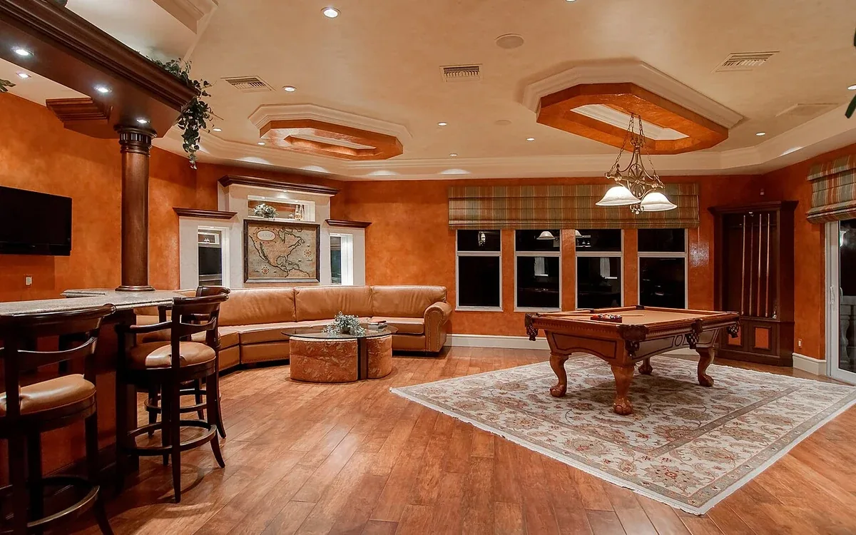 Sofas, chairs and side tables sit around an open wooden floor in a warmly lit living room